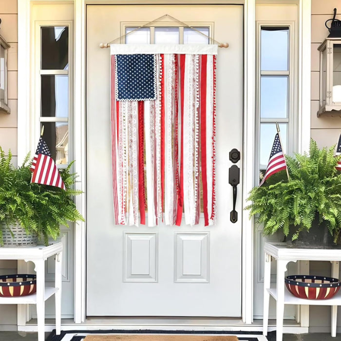 Decorative American flag hanging on a white door with plants and small tables on either side.